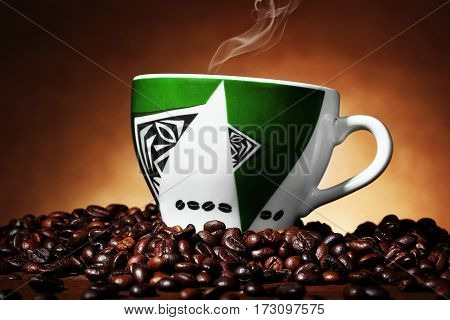Green Cup With African Ornament With Steaming Coffee On Coffee Beans.horizontal Shot