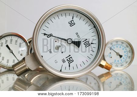 Row of metal steel high pressure gauge meters or manometers with brass fittings on tubing pipeline at LNG or LPG natural gas distribution station plant or factory facility isolated on white background.Pressure gauge in oil and gas production process for m