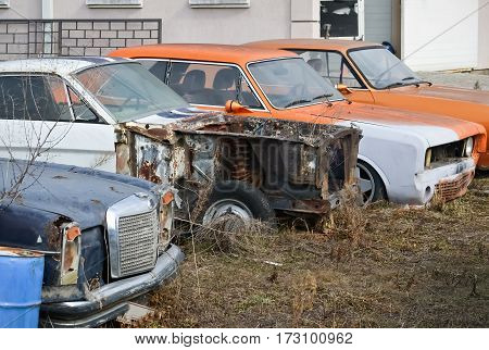 Front part of several old abandoned retro cars in the yard