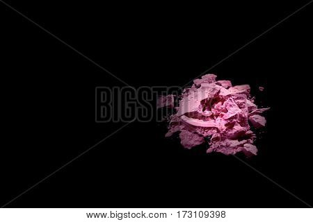 Crushed eye shadow isolated on black background vith spooth light. Beauty and fassion style.Eye shadow of pink color.