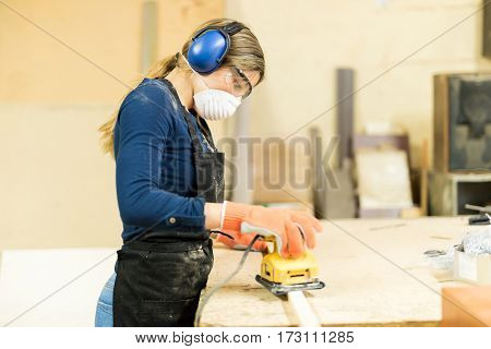 Woman Sanding Some Wood In A Workshop