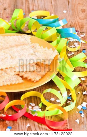 Carnival pastry with confetti on wooden table.