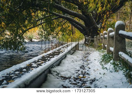 Image of a snow covered path by a river.
