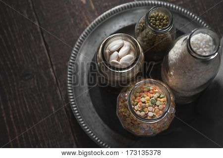 White beans, green beans, lentils and rice in cans on a dark background horizontal