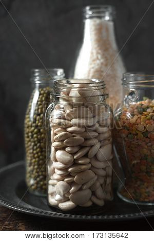 Lentils, white beans, rice in glass bottles vertical
