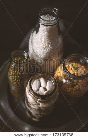 Lentils, white beans, rice in glass bottles side view vertical