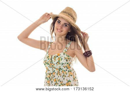 young beautiful girl in sarafan with floral pattern and straw hat looking and smiling on camera isolated on white