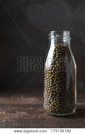 Green beans in a bottle on a dark background vertical