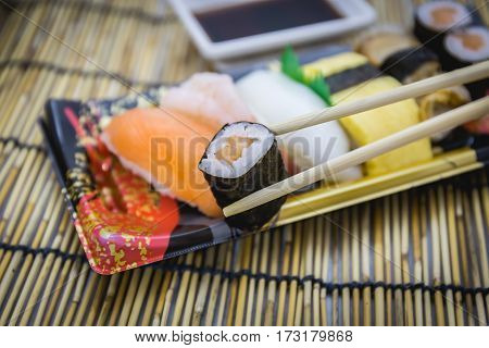 Closeup of sushi set sashimi and rolls served on traditional plate and mat