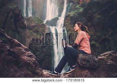 Pensive woman with coffee mug near Ouzoud waterfall in Morocco.