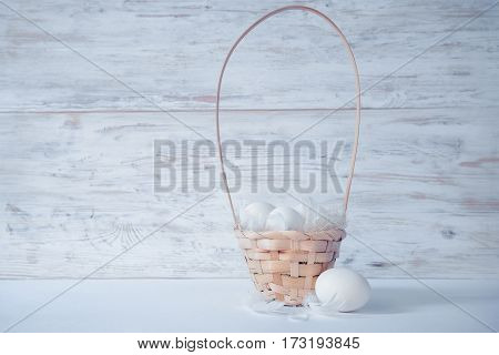 easter eggs in basket on white wooden background