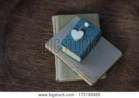 old book and heart lying on a wooden surface.