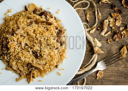 Homemade traditional Italian mushroom risotto on wooden table. Classic Risotto with mushrooms and vegetables served on a white plate. Wild mushrooms risotto. Top view.