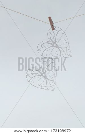 two white fishnet heart hanging on clothespins on a white background. Love Valentine's Day in the background