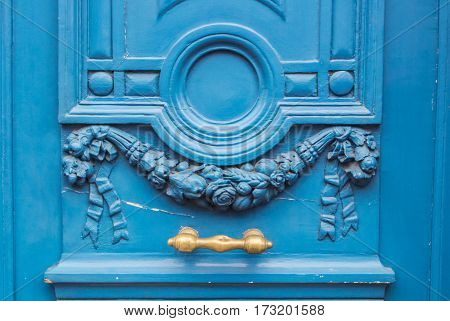 A background of blue wooden old-fashioned decorated door with yellow doorhandle.