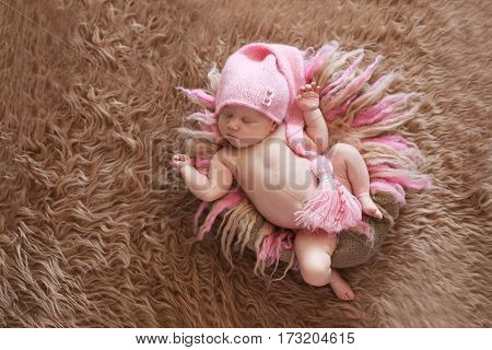 tender sleeping newborn baby in pink cap on a gentle pink background beige fur and wool