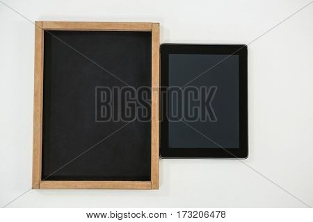 Close-up of digital tablet and slate on white background