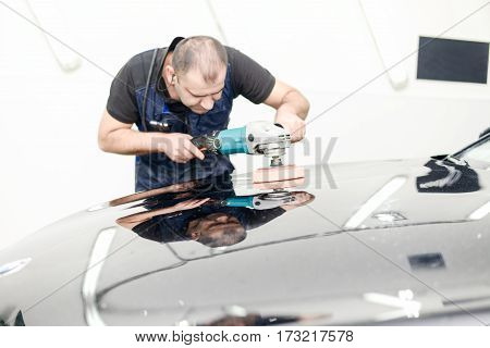 Man on a car wash polishing car with a polish machine
