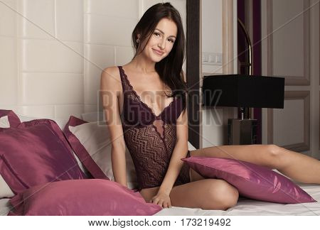 Young Sexy Brunette Woman In Sexy Purple Lace Lingerie Lying On The Bed In Luxury Apartment