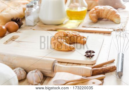 Close up shot of Croissant on wooden cutting board and bekery ingredients on wooden table