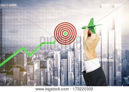 Businessman's hand aiming at taget. Business chart and city background. Targeting concept