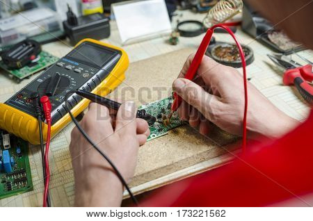 man hands closeup repair electronic device using Multimetr