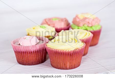 Tasty cupcakes on bright background. vanilla cupcakes with pink and yellow cream selective focus
