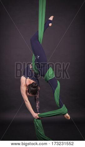 Girl's aerial acrobatics in the paintings - dark background. Studio photography of circus performers
