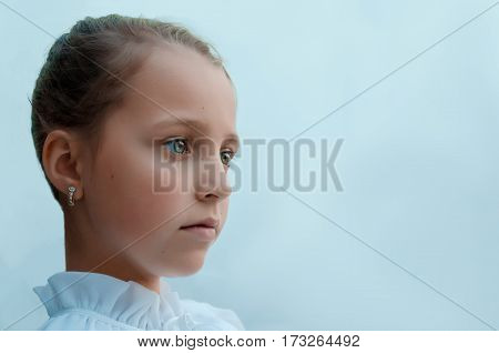 Girl sad and specifically looks into the distance on a uniform blue background