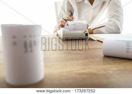 Business accountant or financial adviser making calculations using adding machine.