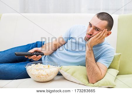 Man changing channels and feeling bored at his home.