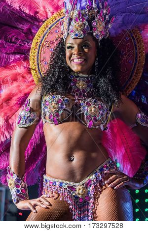 MOSCOW, RUSSIA- JANUARY 2017: Brazilian carnival show. Beautiful girl bright colorful carnival costume dark background. Smiling Afro-Americans woman samba dancer pink carnival costume black background