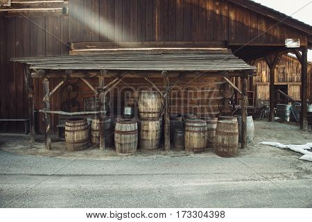 Old vintage Barrels near retro style wooden barn. Wild west concept photo.