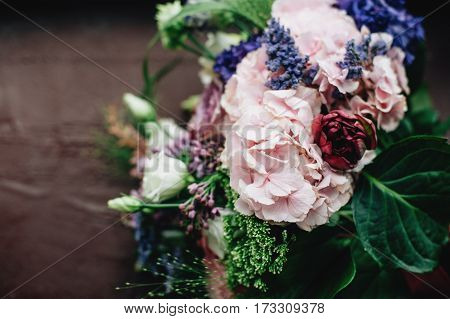 Tenderless bouquet with bow and ribbons in green and pink and blue colours on brown background