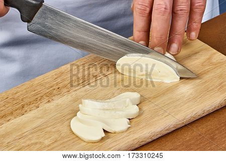 the process of cutting the cheese mozzarella on a cutting board closeup preparing meals