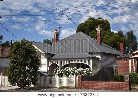 suburban house on sunny day with grey roof and white picket fence