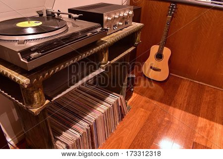 vintage record player with records in foreground and guitar in background