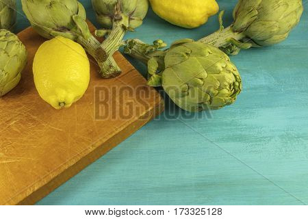 Artichokes and lemons on vibrant turquoise texture with a place for text