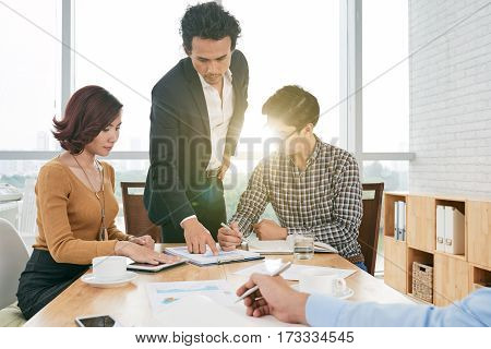 Financial manager explaining diagram to coworkers to meeting