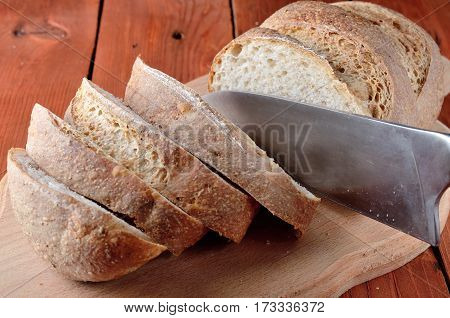 Loaf Of Bread With Sliced Pieces On A Cutting Board And Knife, Close-up.