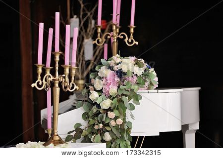 Composition with white piano and candles, candlesticks and rose petals