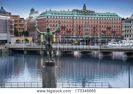 STOCKHOLM SWEDEN - AUGUST 20 2016: View of luxury hotel Grand Hotel at Stockholm waterfront and Sun Singer Statue at Stromparterren Park from Norrbro in Stockholm Sweden on August 20 2016.