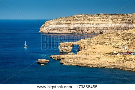 Gozo Malta - The Azure Window and Dwejra bay on a beautiful summer day with sail boat and clear blue sky