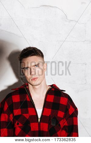 Vertical image of Serious Hipster in shirt posing in studio and looking at camera