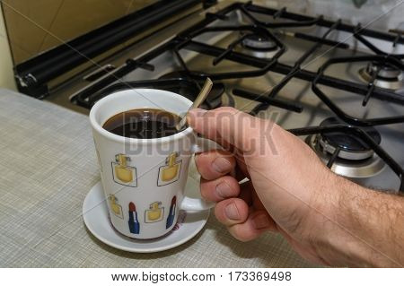 Hand with full cup of morning dose of instant coffee