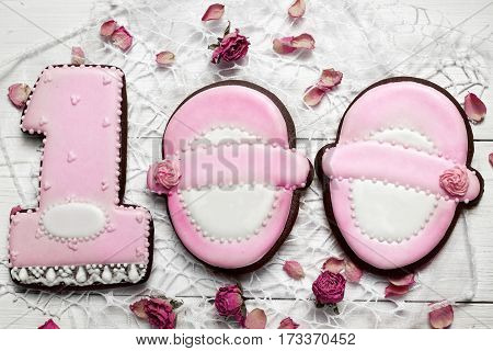 Cookies With Glaze In The Form Number One And Shoes With Petals Of Dried Rosses . On White Wooden Su