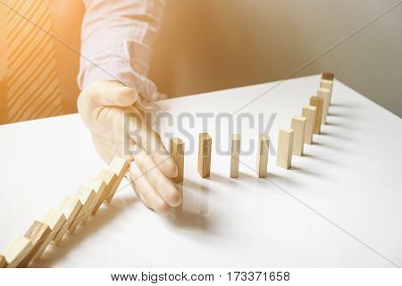 a male hand stopping the domino effect. retro style image executive and risk control concept