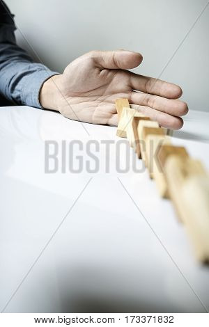 A Male Hand Stopping The Domino Effect. Retro Style Image Executive And Risk Control Concept