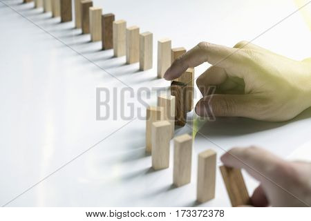 a male hand stopping the domino effect. retro style image executive and risk control concept