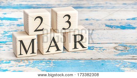 March 23th. Wooden cubes with date of 23 March on old blue wooden background.